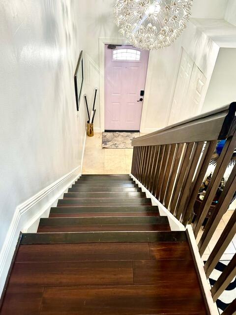 stairs with an inviting chandelier and hardwood / wood-style floors