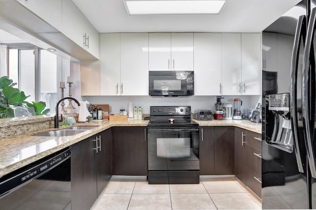 kitchen with light stone countertops, black appliances, kitchen peninsula, white cabinetry, and light tile patterned floors