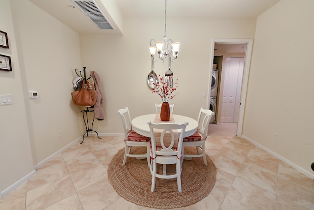 tiled dining area with a notable chandelier and stacked washer / dryer