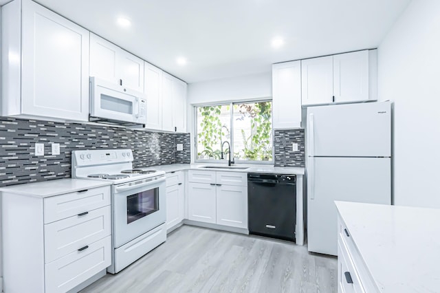 kitchen with white appliances, white cabinetry, sink, and light hardwood / wood-style flooring