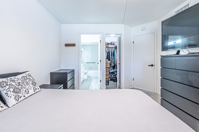 bedroom with hardwood / wood-style flooring, a closet, ensuite bathroom, and a walk in closet