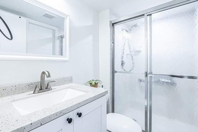 bathroom with vanity, toilet, and a shower with door