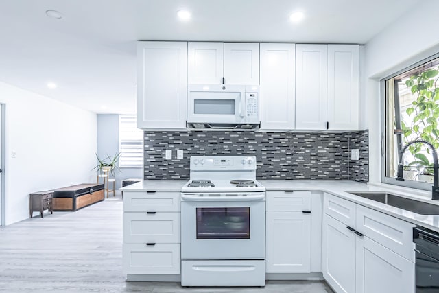 kitchen with white cabinets, backsplash, white appliances, light wood-type flooring, and sink