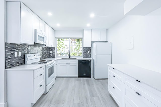 kitchen with tasteful backsplash, sink, white cabinets, light hardwood / wood-style flooring, and white appliances