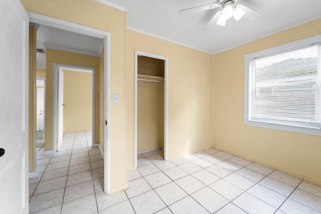 unfurnished bedroom with ceiling fan, light tile patterned flooring, a closet, and crown molding