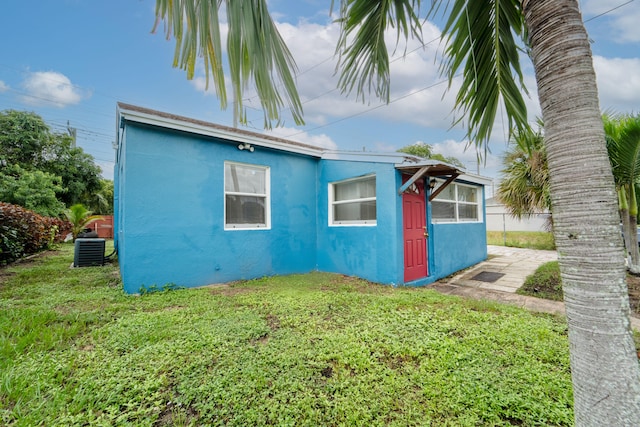 exterior space with central air condition unit and a yard