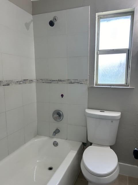 full bathroom featuring tiled shower / bath, vanity, toilet, and tile patterned flooring