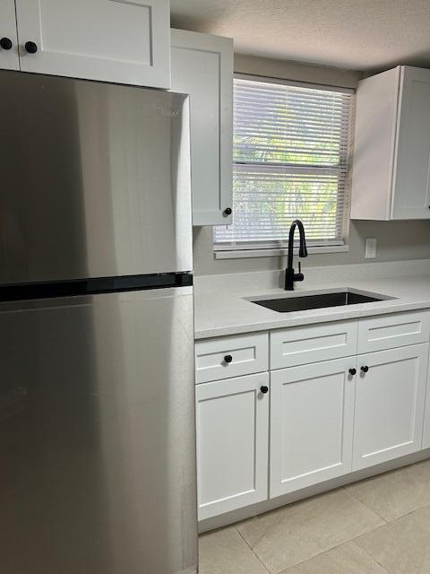 kitchen with stainless steel appliances, white cabinetry, and light tile patterned floors