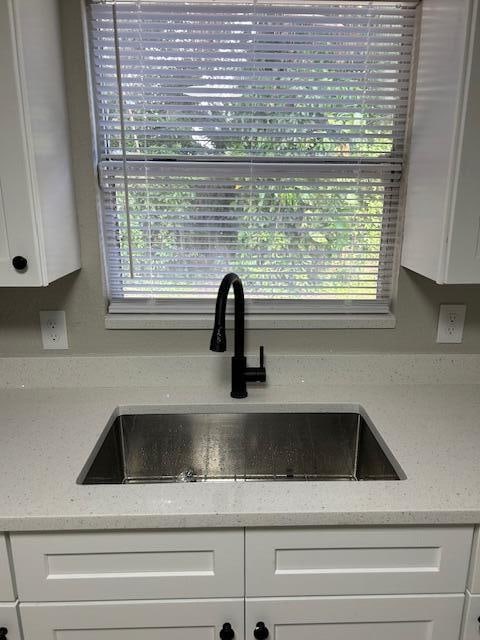 details featuring light stone counters, sink, and white cabinets