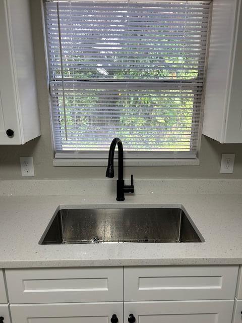 kitchen with sink, stainless steel fridge, and white cabinets