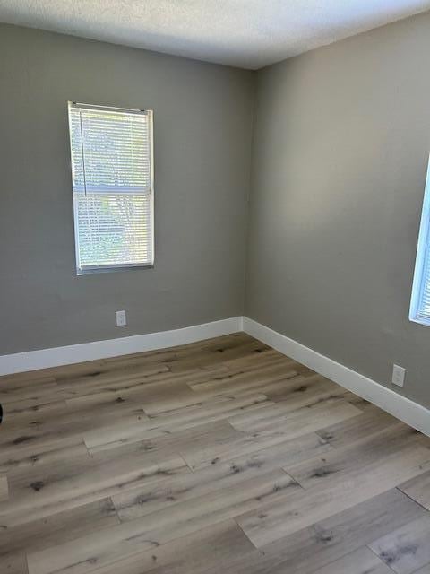 empty room featuring a textured ceiling and light hardwood / wood-style flooring