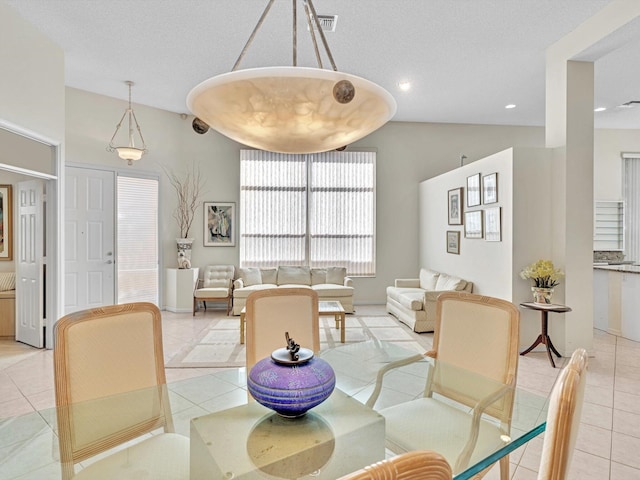 tiled dining space featuring a textured ceiling and vaulted ceiling