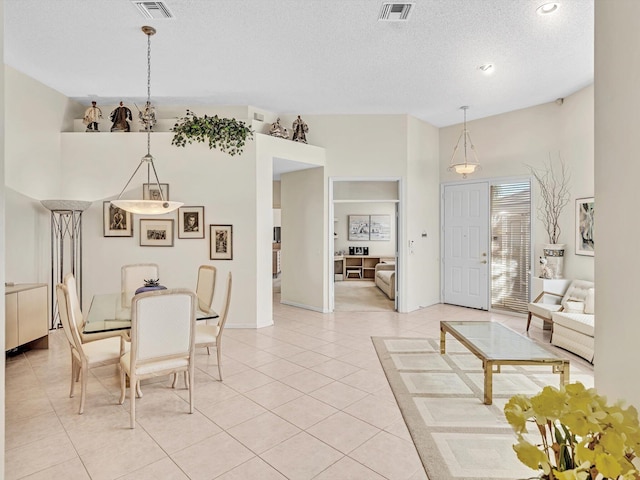 dining room with a high ceiling, a textured ceiling, and light tile patterned floors