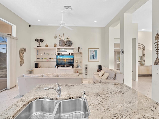 kitchen featuring ceiling fan, light tile patterned flooring, light stone countertops, and sink