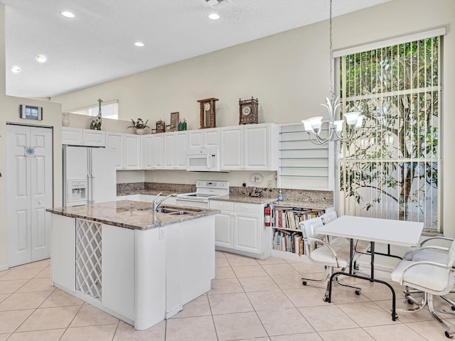 kitchen with white cabinets, white appliances, a center island with sink, and plenty of natural light