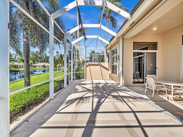 view of patio with a lanai and a water view