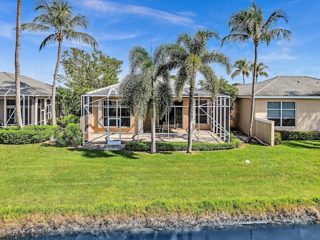 back of property with a water view, a yard, a lanai, and a patio area