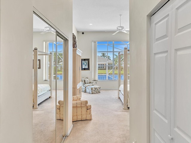 hall with light colored carpet, a textured ceiling, and plenty of natural light