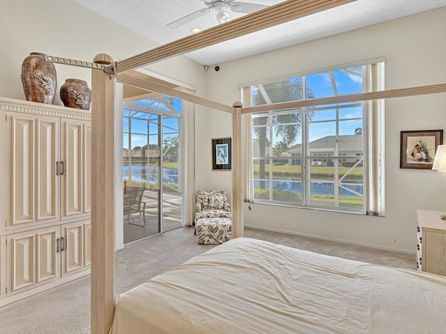 carpeted bedroom with ceiling fan, a textured ceiling, access to exterior, and a water view