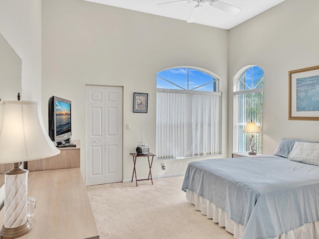 bedroom featuring ceiling fan, hardwood / wood-style flooring, and a towering ceiling