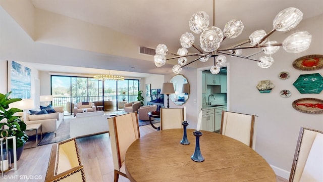 dining space with light hardwood / wood-style floors, sink, and a notable chandelier