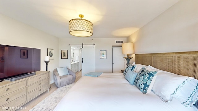 bedroom featuring a barn door and light hardwood / wood-style flooring