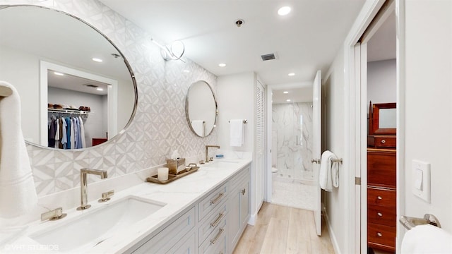 bathroom with vanity, a tile shower, hardwood / wood-style floors, and decorative backsplash