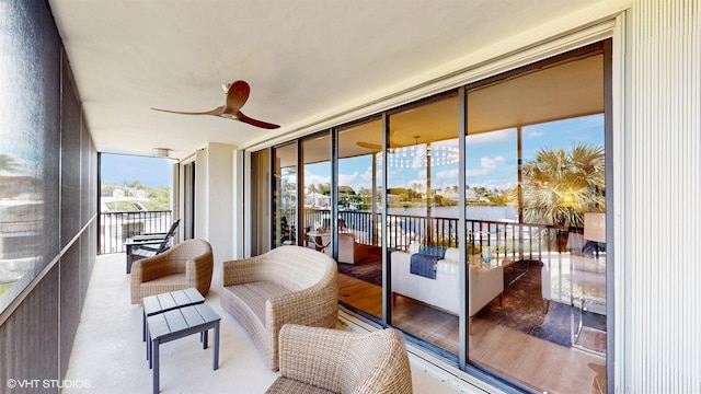 sunroom featuring ceiling fan and a water view