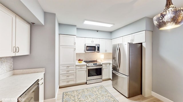 kitchen with tasteful backsplash, white cabinets, hanging light fixtures, stainless steel appliances, and light hardwood / wood-style flooring