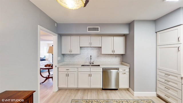 kitchen featuring sink, white cabinets, decorative backsplash, stainless steel dishwasher, and light hardwood / wood-style flooring