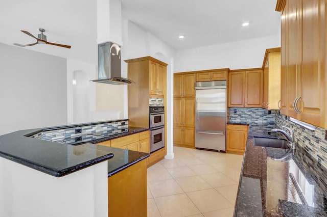 kitchen with kitchen peninsula, stainless steel appliances, dark stone counters, and sink