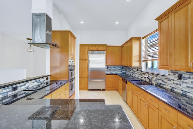 kitchen with sink, dark stone counters, decorative backsplash, island range hood, and appliances with stainless steel finishes