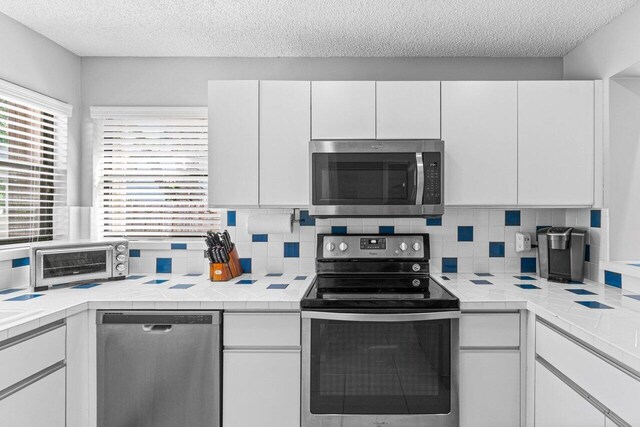 kitchen with white cabinetry, appliances with stainless steel finishes, and light tile patterned floors