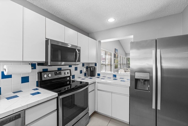 kitchen featuring tasteful backsplash, vaulted ceiling, stainless steel appliances, and white cabinets