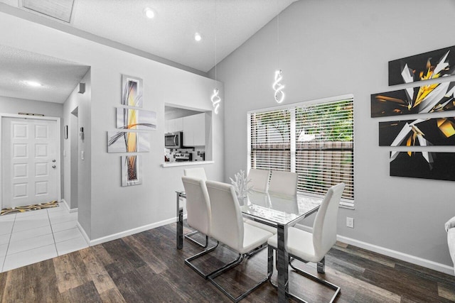 dining area featuring a textured ceiling, hardwood / wood-style floors, and high vaulted ceiling