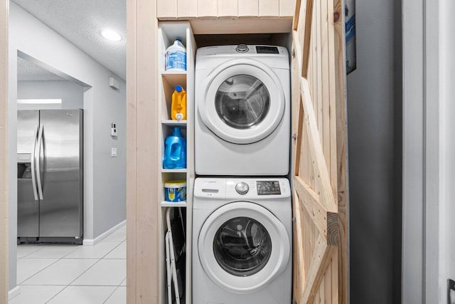 laundry room with stacked washer and clothes dryer, a textured ceiling, and light tile patterned floors