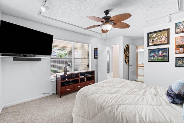 bedroom featuring light carpet, a textured ceiling, rail lighting, and ceiling fan