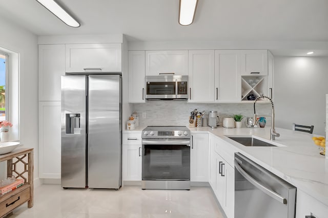 kitchen featuring white cabinets, appliances with stainless steel finishes, sink, and light stone countertops