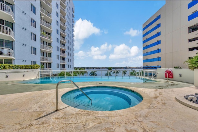 view of swimming pool with pool water feature and a hot tub