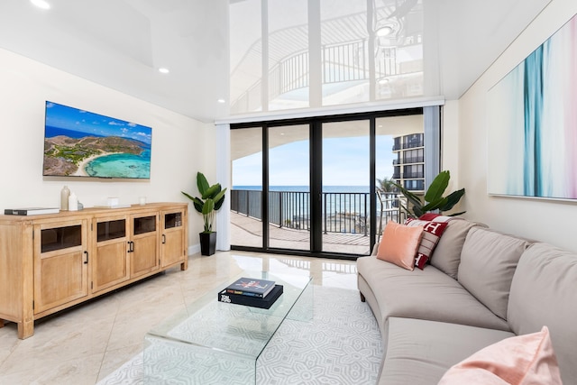 tiled living room with a wall of windows, a water view, and a towering ceiling