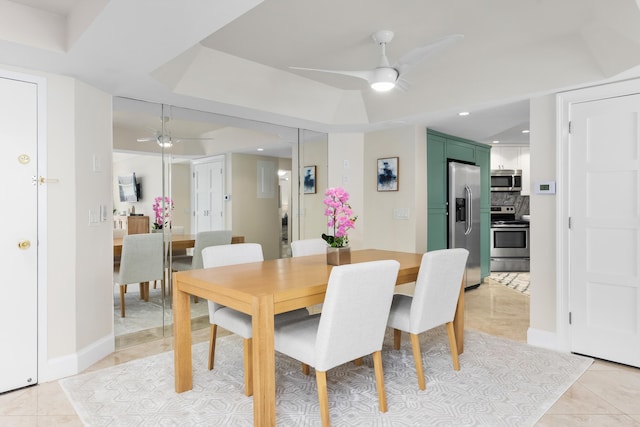 tiled dining space featuring ceiling fan and a raised ceiling