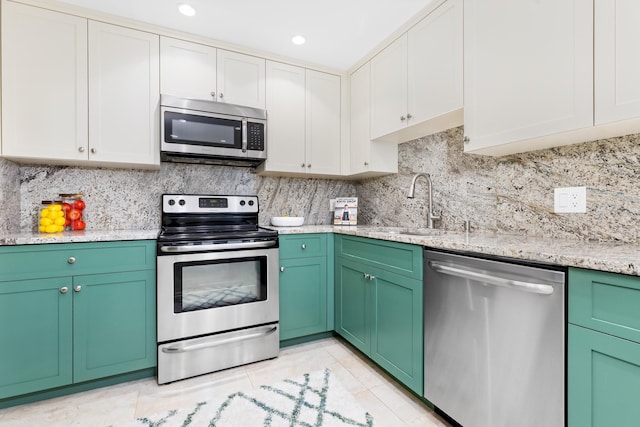 kitchen featuring white cabinetry, stainless steel appliances, sink, backsplash, and light tile patterned floors