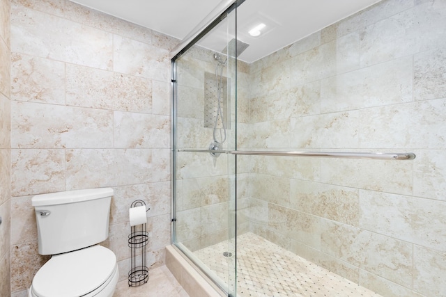 bathroom featuring toilet, tile walls, and walk in shower