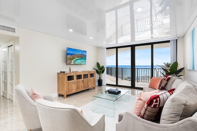 living room featuring a towering ceiling, plenty of natural light, and expansive windows