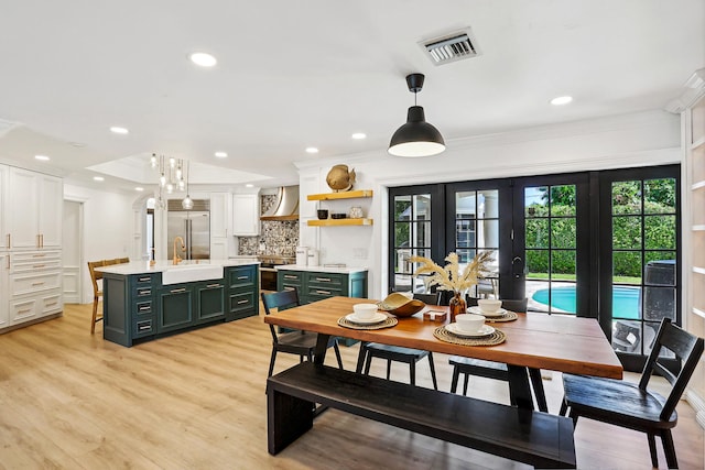 dining space featuring crown molding, french doors, sink, and light wood-type flooring