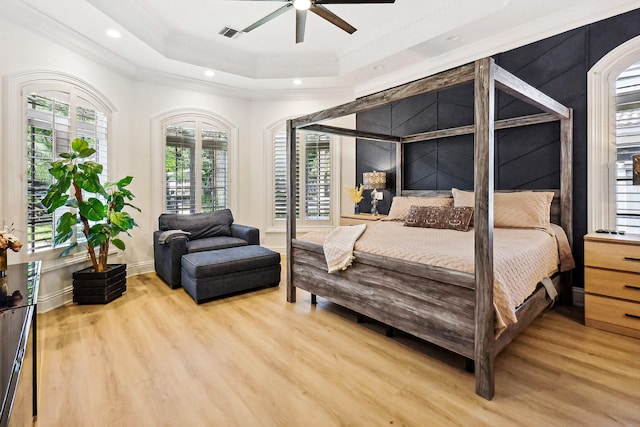 bedroom with a tray ceiling, ceiling fan, hardwood / wood-style floors, and ornamental molding