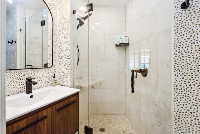 bathroom featuring vanity, a shower with door, and backsplash