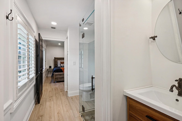 bathroom with wood-type flooring, vanity, toilet, and an enclosed shower