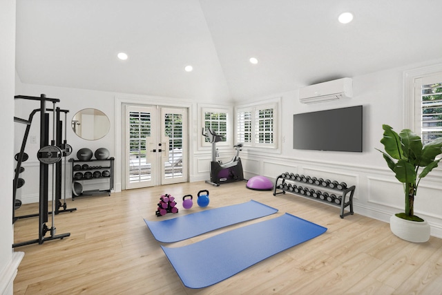 exercise room featuring a wall mounted air conditioner, french doors, light wood-type flooring, and lofted ceiling