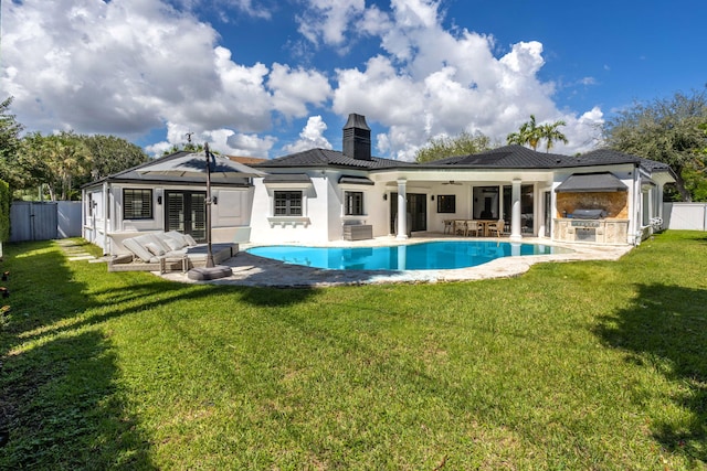 rear view of property with a lawn, ceiling fan, a patio area, and exterior kitchen